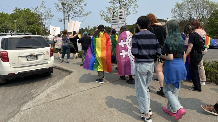 Des gens de Matane, avec des drapeaux LGBTQ+, marchent dans le centre-ville. 