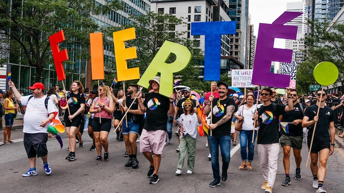 Des festivaliers portent les couleurs de la fierté et brandissent des lettres formant le mot « fierté ». 