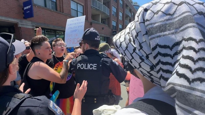 En plein défilé de la Fierté à Halifax, des policiers s'adressent à des participants qui semblent en colère. 