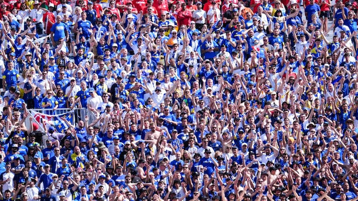 Une dense foule dans les gradins, habillée de rouge et de bleu.