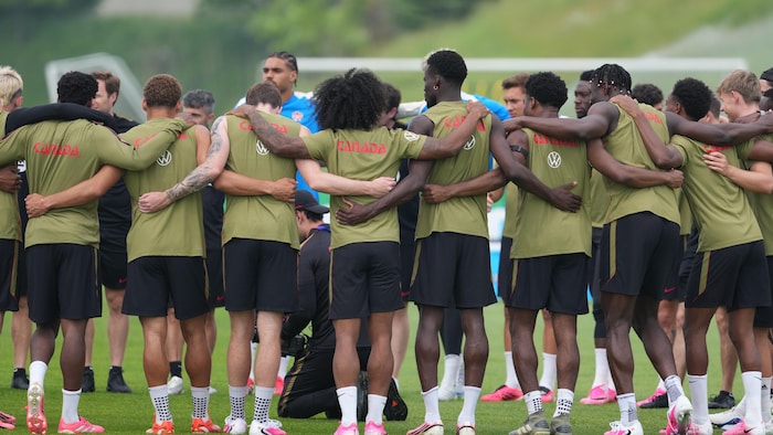 Les joueurs de l’équipe masculine de soccer se tenant en cercle par les épaules au centre du terrain