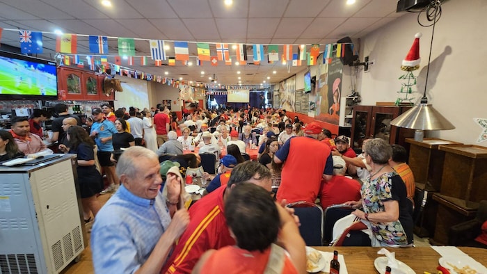 Des personnes arborant des maillots aux couleurs de l'équipe de l'Espagne sont rassemblés dans un bar.