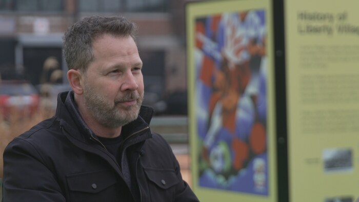 Portrait de Sean Mayers devant une affiche de la Coupe du monde de la FIFA, dans le quartier de Liberty Village, à Toronto.