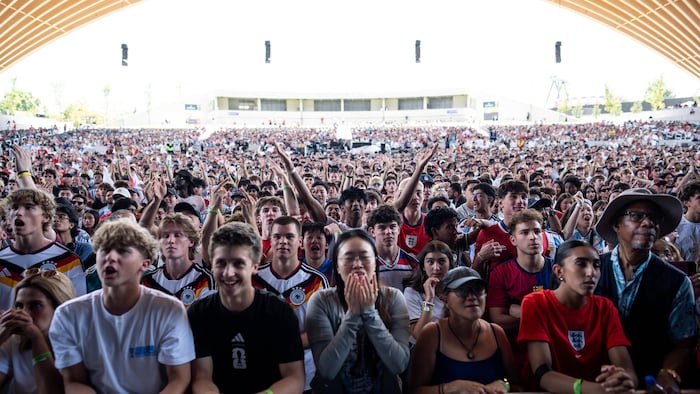 Une foule dense de jeunes partisans portant des maillots de soccer variés réagit avec émotion sous la grande structure en bois de l'amphithéâtre du PNE.