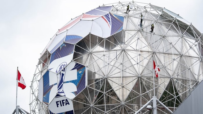 Des travailleurs transforment le dôme de Science World en un ballon de soccer géant. 