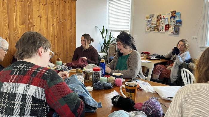 Karine Verpillot autour d'une table remplie de laine, boutons, tissus.