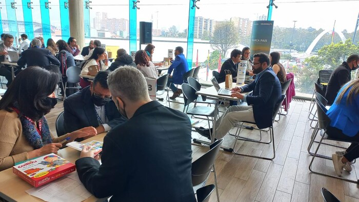 Des personnes sont assises à des tables dans un salon vitré lors d'une activité de jumelage entre des maisons d'édition canadiennes et latino-américaines.