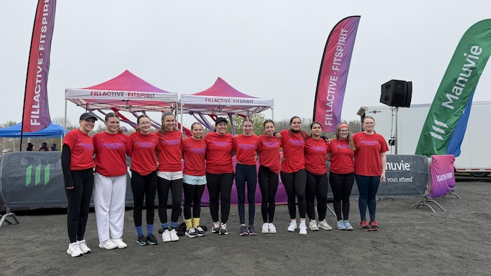 Un groupe de jeunes filles en tenue sportive se tient ensemble à l’extérieur.