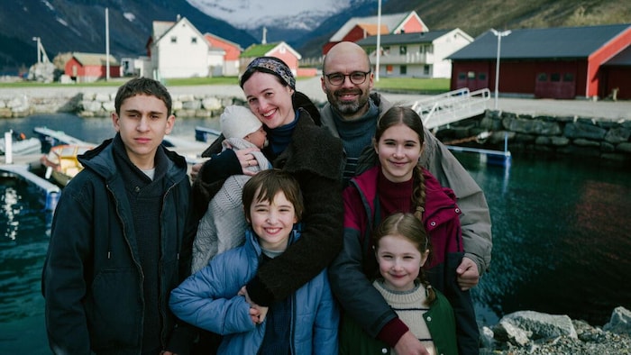 Une famille de cinq enfants devant un petit port.