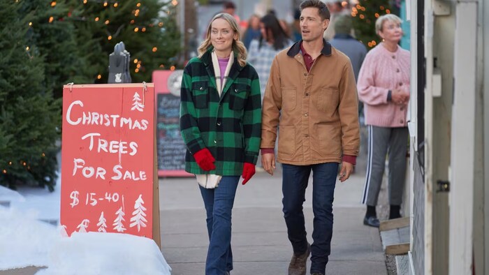 Un couple marche dans une rue bien décorée pour Noël.