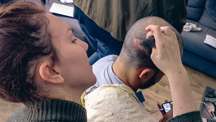 Une femme essuie une fausse blessure sur une tête rasée.