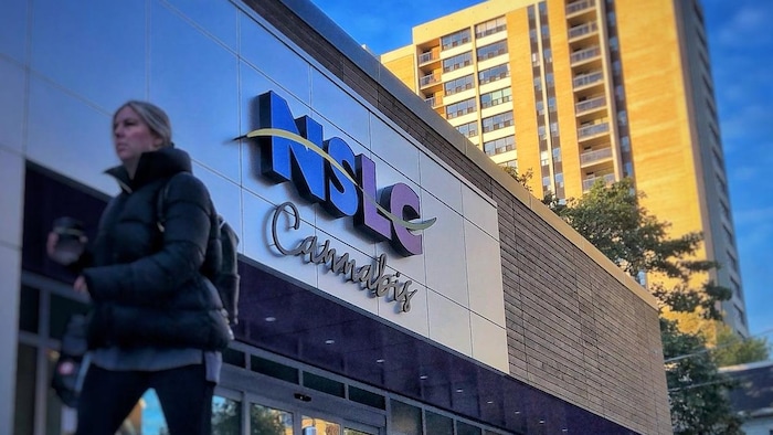 Une femme marche devant un dispensaire de la NSLC.