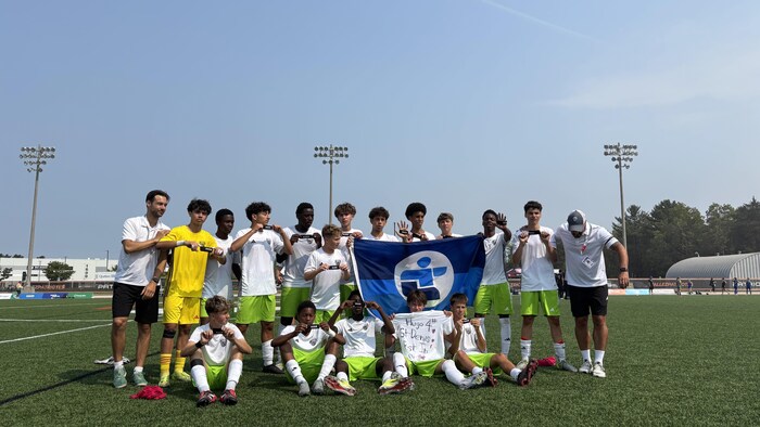 Les jeunes brandissent la banderole des Jeux du Québec et un chandail qui honore leur ami Hugo.