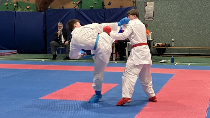Un concurrent évite un coup de pied au visage de la part de son adversaire lors d'un combat de karaté.