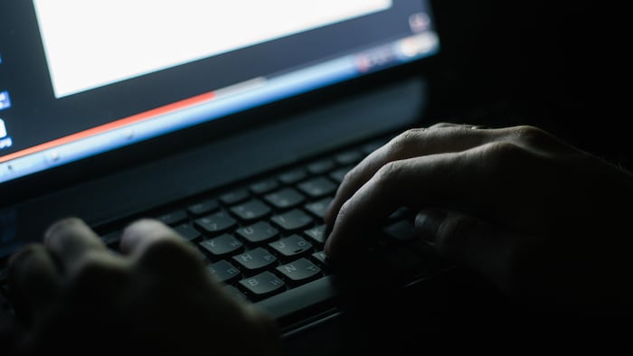 Des mains sur un clavier d'ordinateur dans l'obscurité.