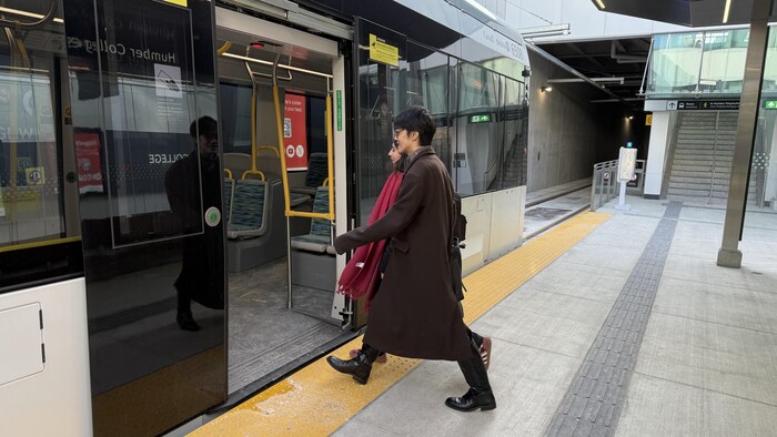 Deux usagers montent à bord d'un train léger de la ligne Finch Ouest à Toronto, le 8 décembre 2025.