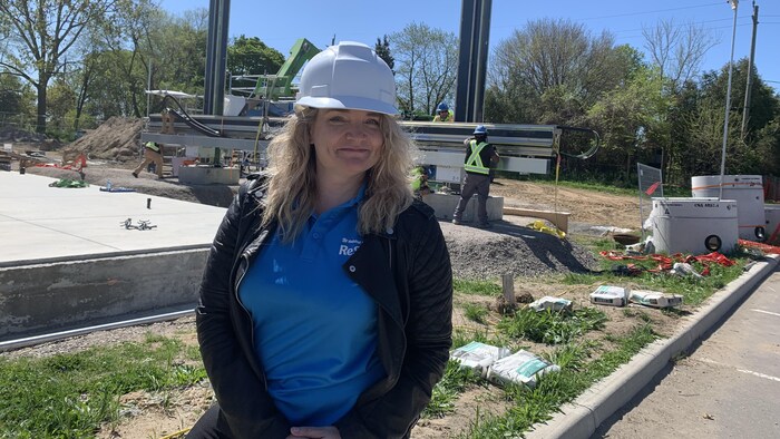 Fiona Caughlin porte un casque de sécurité sur un chantier de construction et regarde tout droit vers la caméra.