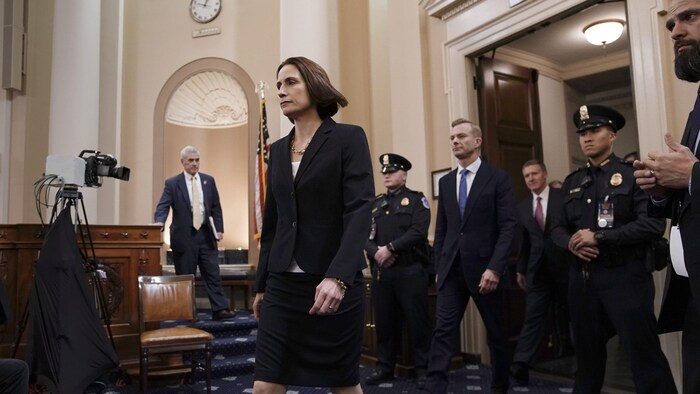 Fiona Hill s'avance dans une salle du Capitole entourée d'hommes, dont des agents de sécurité.