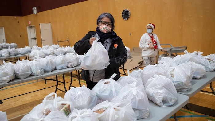 Assembly of First Nations National Chief RoseAnne Archibald, front left, helps Arlene Haldane distribute Christmas hampers containing turkeys and other food to members of the Musqueam First Nation in Vancouver on Dec. 17, 2021.