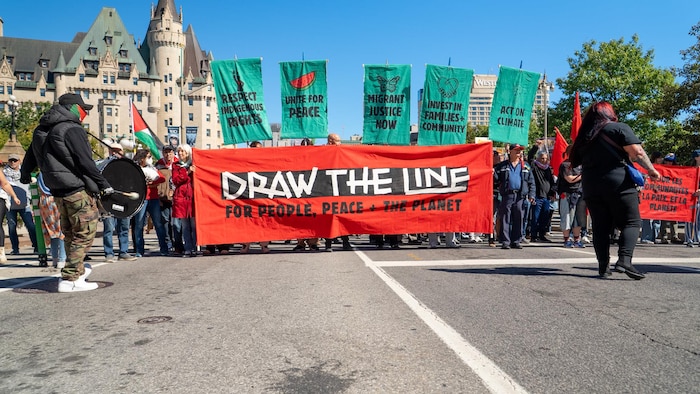 Des manifestants brandent une pancarte sur lequel est écrit en anglais «fixons les limites» sur la rue Wellington.