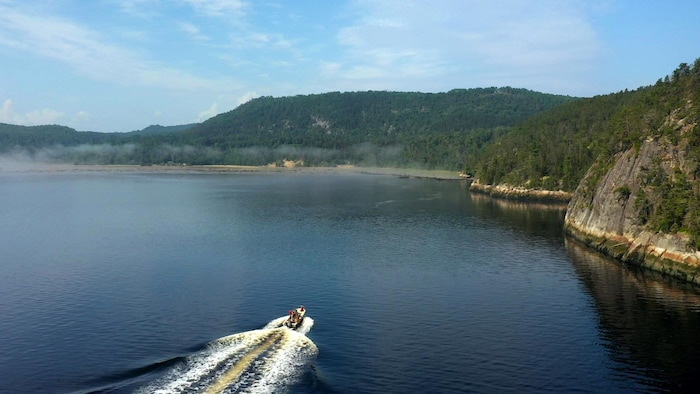 Un petit bateau circule sur les eaux du fjord.