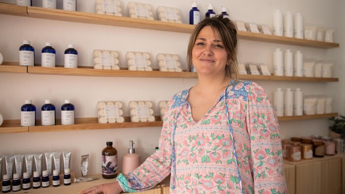 Une femme devant des étalages de bougies et de parfums.