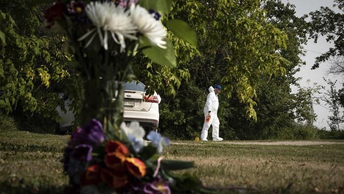 محقق في مسرح الجريمة في ويلدون في ساسكاتشِوان وباقة زهور تكريماً لإحدى ضحايا هجمات السكاكين في 4 أيلول (سبتمبر) 2022.