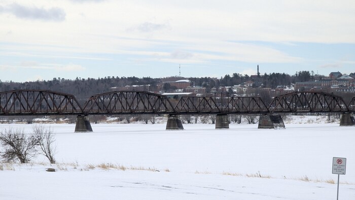 Un pont en métal enjambe un fleuve gelé.