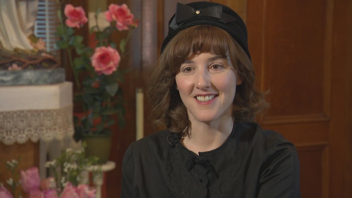 Une femme portant un chapeau noir sourit.