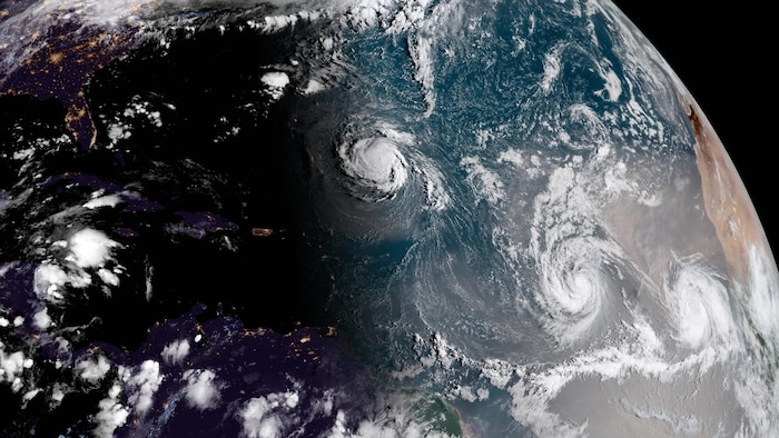 Vue sur l'océan Atlantique de l'espace où l'on voit la formation de nuages en spirale propres aux ouragans à trois endroits distincts, soit les tempêtes tropicales Florence, Isaac et Helene.