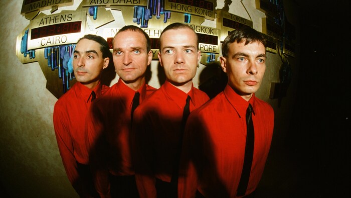 Les quatre membres du groupe de musique portent la même chemise et regardent dans des directions différentes.
