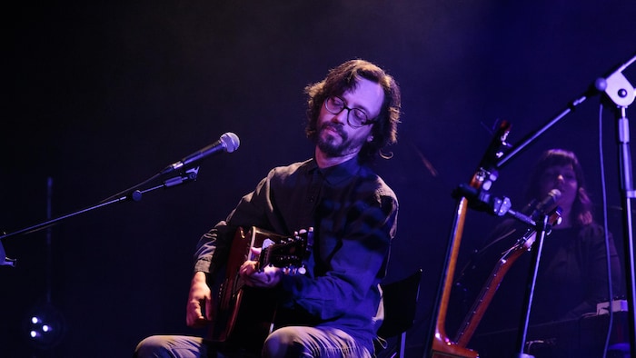 un chanteur joue à la guitare sur scène  