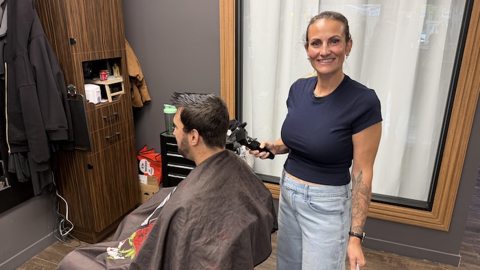 Une coiffeuse en train de coiffer un homme. 