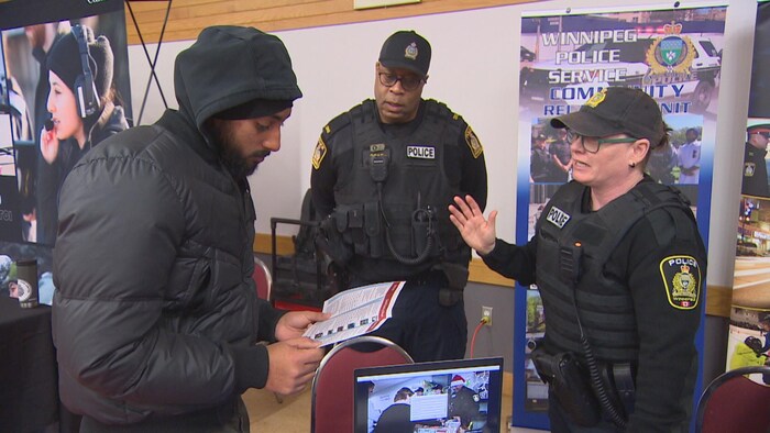 Une policière parle avec une personne, et un autre policier les regarde, le 22 février 2025 à Winnipeg.
