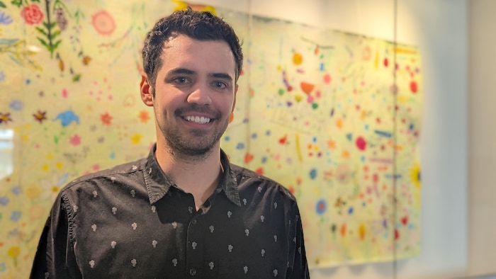M. Clément pose devant une toile d'artiste.
