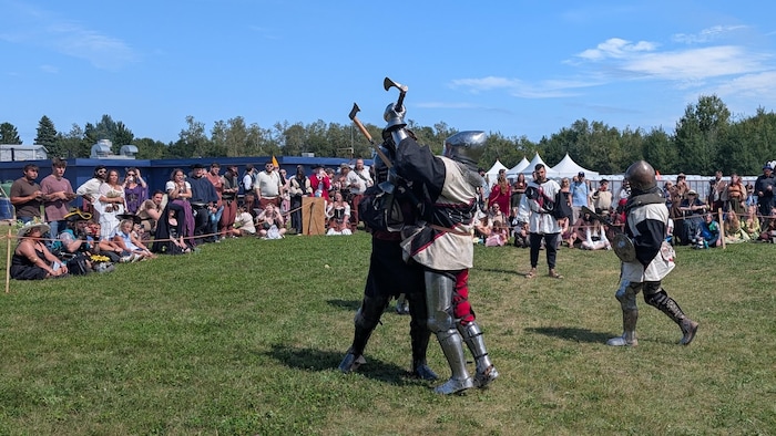 Deux hommes portant des armures se donnent des coups de hache.