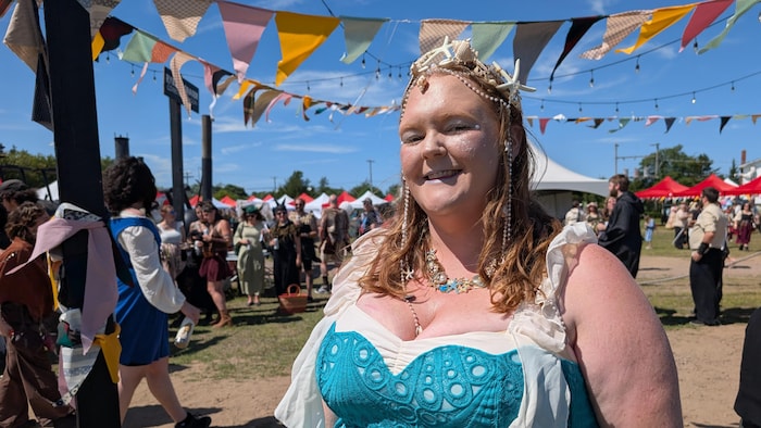 Une femme souriante portant une robe inspirée du Moyen-Âge.