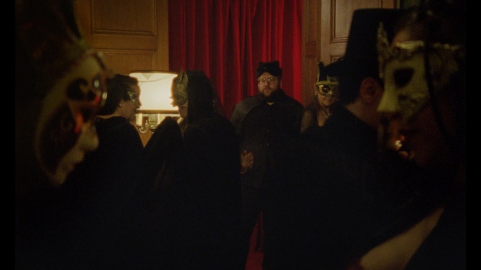 Un homme tient son verre dans une soirée masquée.