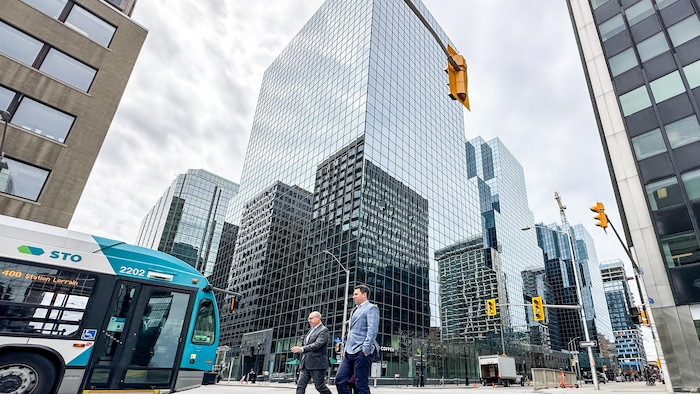 Un édifice du centre-ville d'Ottawa, des piétons et un autobus de la Société de transport de l'Outaouais, le 29 avril 2024. 