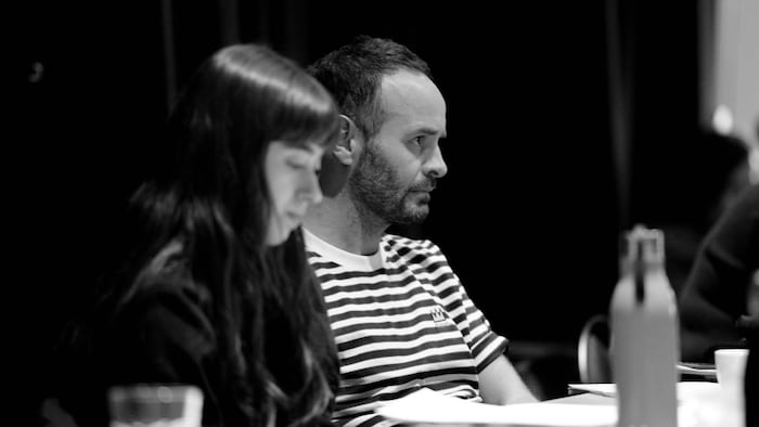 Michel-Maxime Legault et une femme assise à ses côtés regardent une répétition de théâtre.