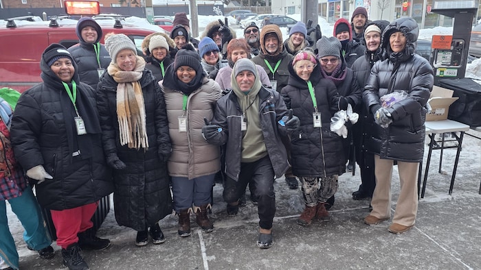 Un groupe de bénévoles de Food for Now sourient pour une photo sur un trottoir pendant l'hiver.
