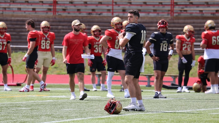 Ouellette s'apprête à lancer le ballon à l'entrainement, sous l'oeil de Charland en arrière-plan.