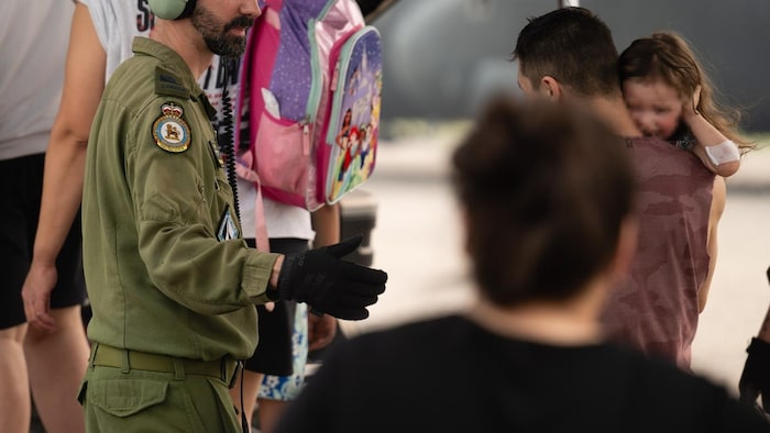 Un militaire aide à faire monter des personnes dans un avion.