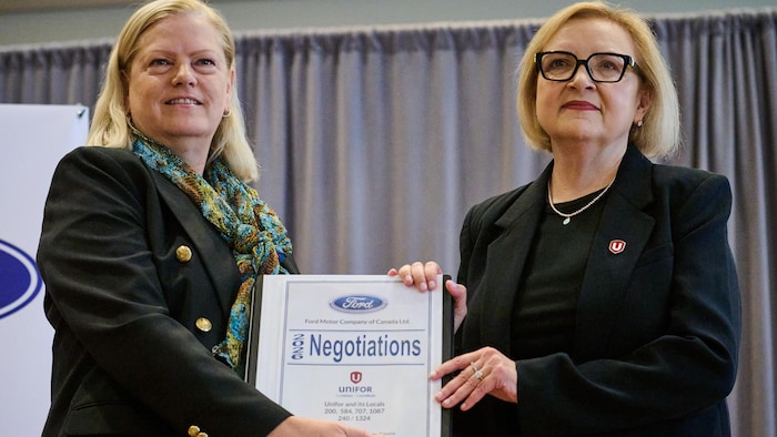 Meredith Keenan et Lana Payne, s’échangent un dossier de négociation pour marquer l’ouverture des négociations entre Unifor.