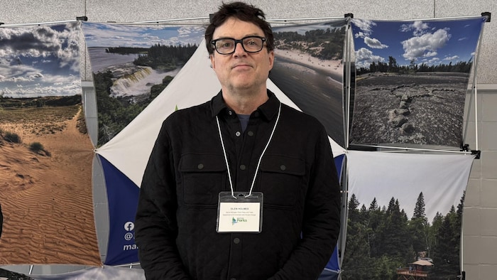Un homme se tient debout devant une table de Parcs Manitoba.