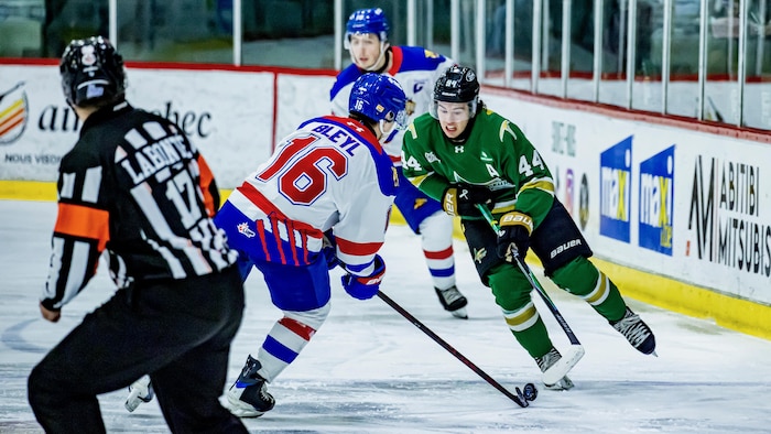 Un joueur des Foreurs affronte un joueur des Wildcats pour frapper la rondelle.