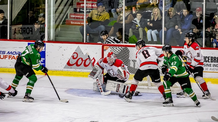 Un joueur des Foreurs est positionné dans l'enclave avec la rondelle sur sa palette et tente de déjouer la vigilance du gardien des Huskies.