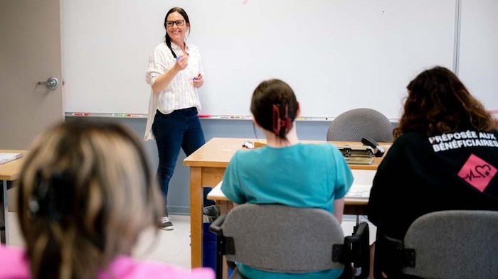 Dans une salle de classe une femme donne un cours.