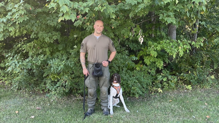 Un homme et son chien regardent la caméra en souriant.