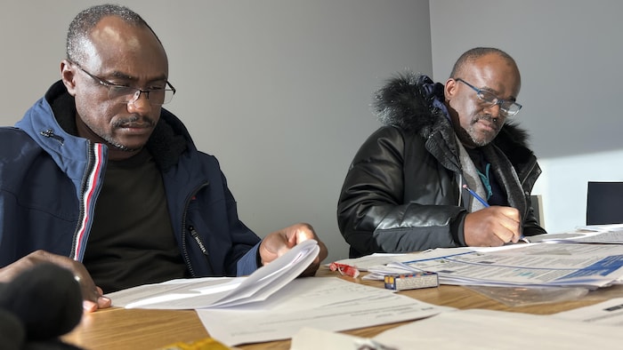 Deux hommes concentrés devant leurs formulaires.